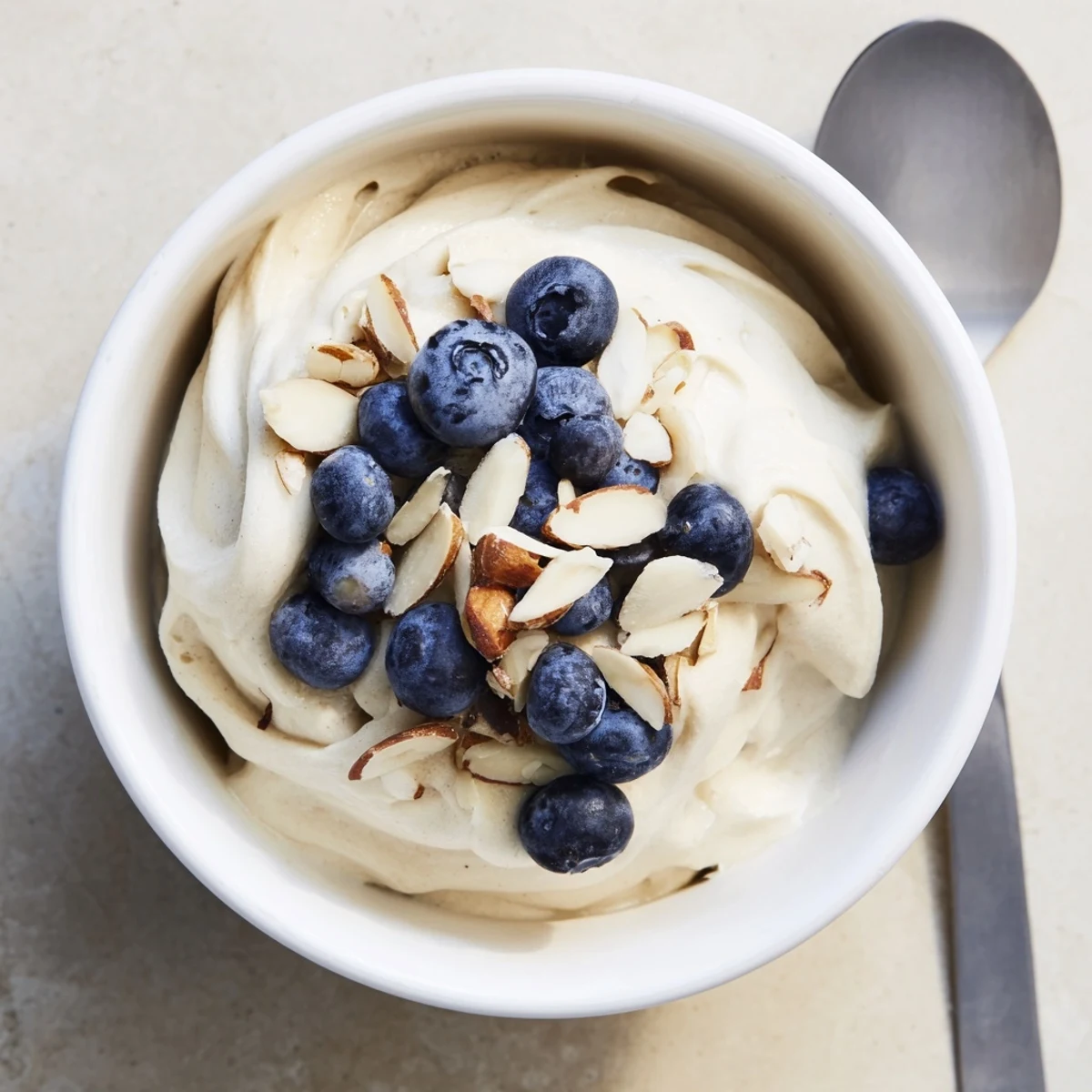 Homemade banana nice cream recipe scooped into glass bowls with colorful fruit garnish