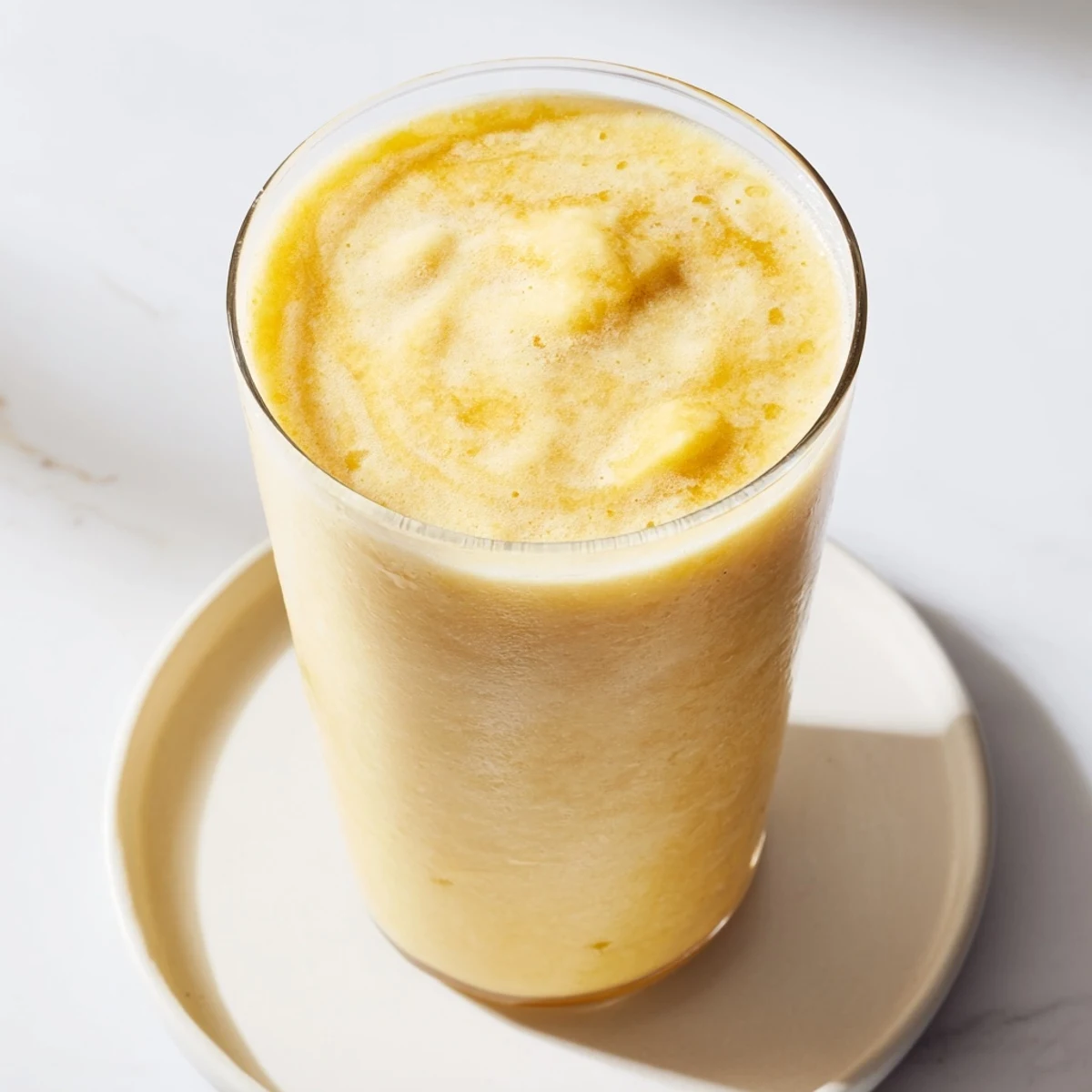 Creamy yellow Tropical Pineapple Mango Smoothie Recipe poured into tall glasses with ice cubes