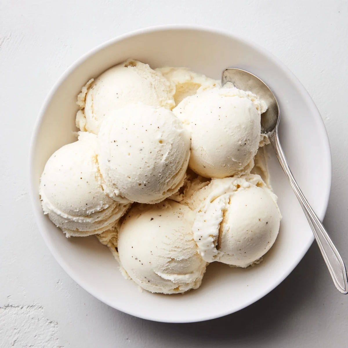 Rich custard-based vanilla ice cream being scooped from a vintage ice cream maker with smooth texture