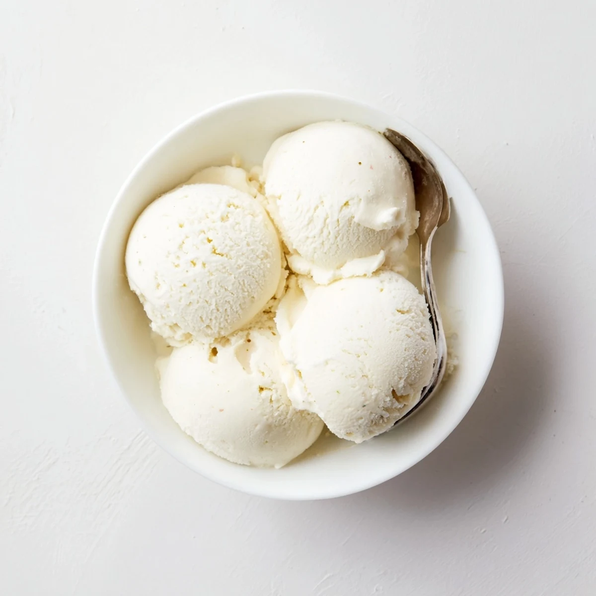 Creamy homemade vanilla ice cream scooped into a chilled glass bowl with fresh mint garnish