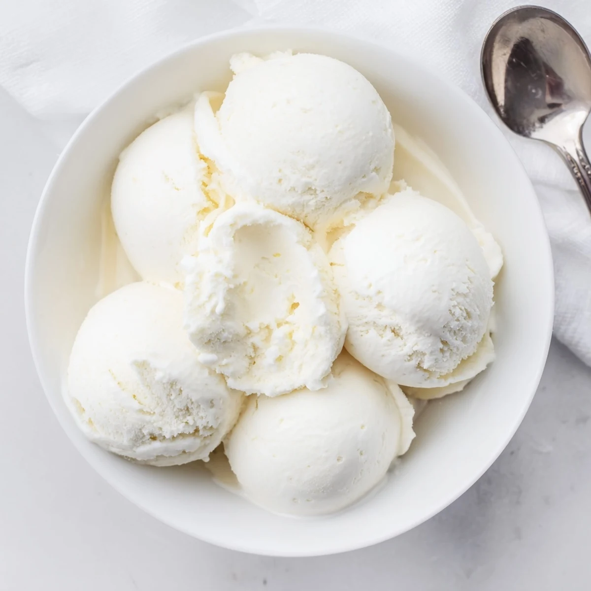 Golden vanilla bean ice cream swirl displayed in a white ceramic bowl ready for summer dessert