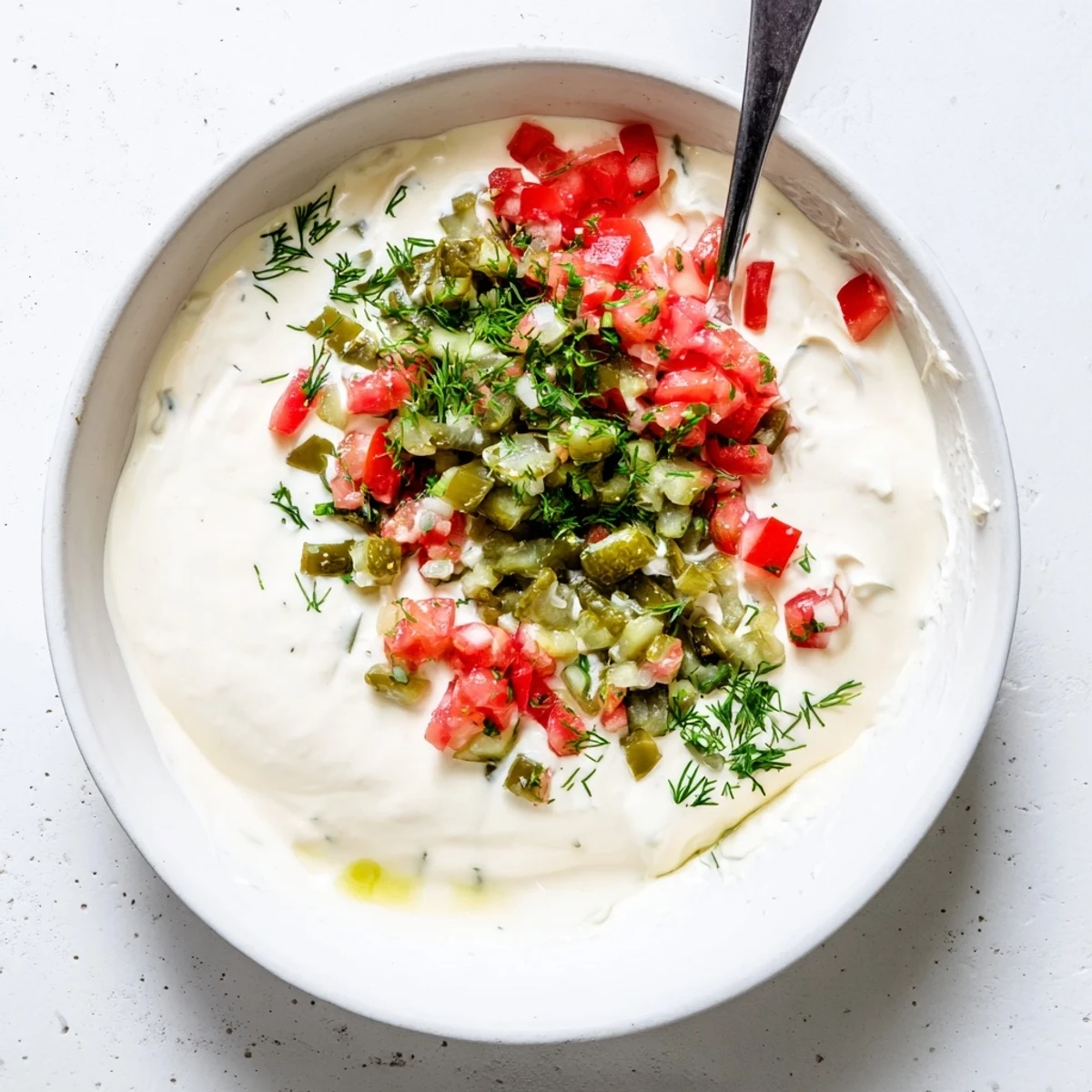 White bowl filled with creamy Grillos pickle de gallo ranch dip garnished with fresh herbs and pico de gallo