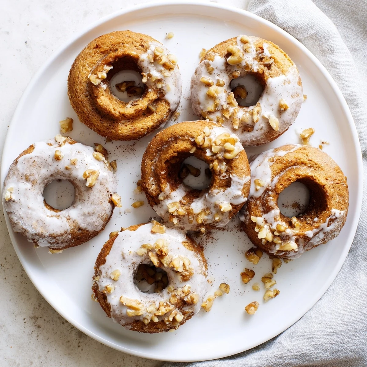 Golden banana bread donuts with cinnamon sugar glaze drizzled over moist, fluffy cake rings