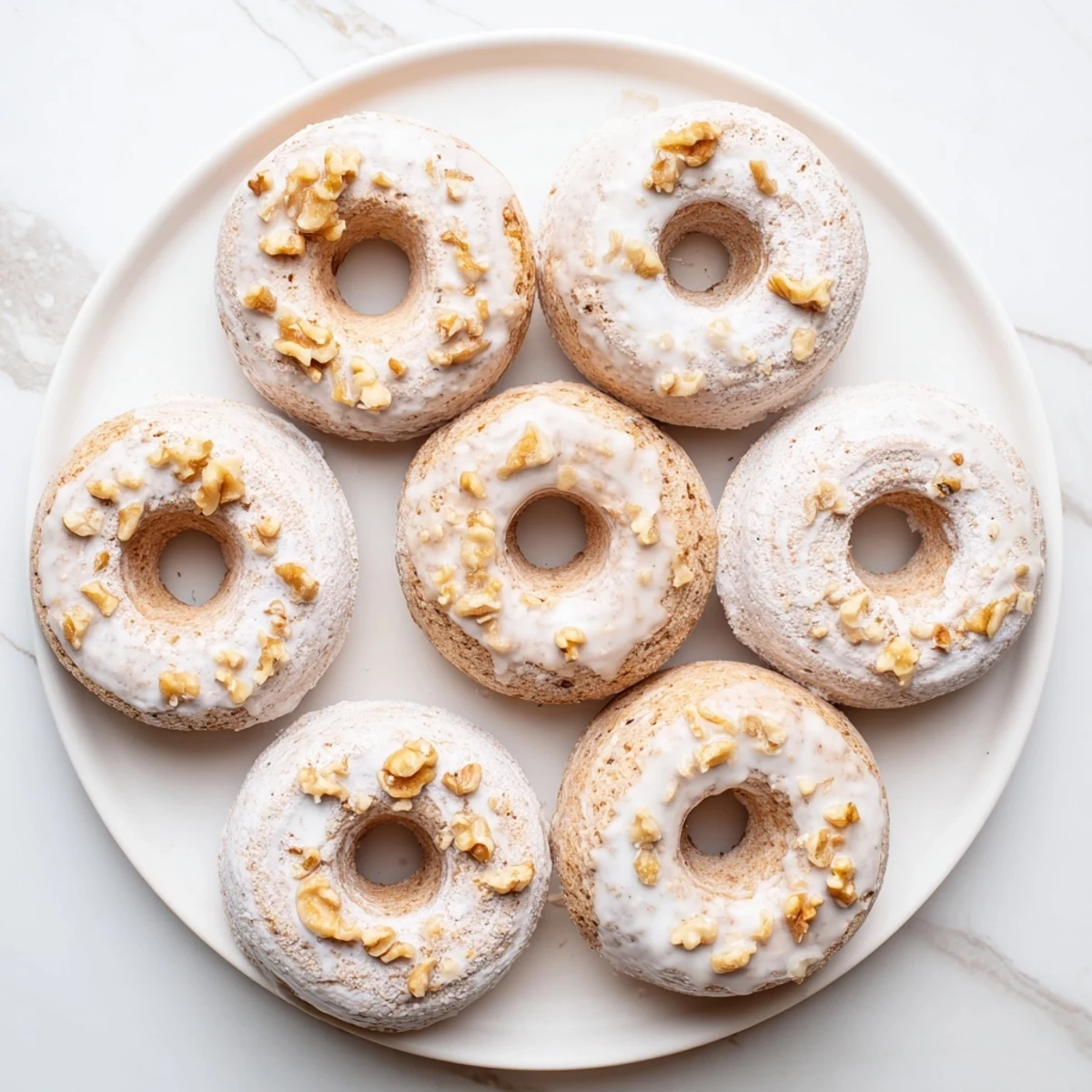 Soft baked banana bread donuts topped with sweet powdered sugar glaze and ground cinnamon