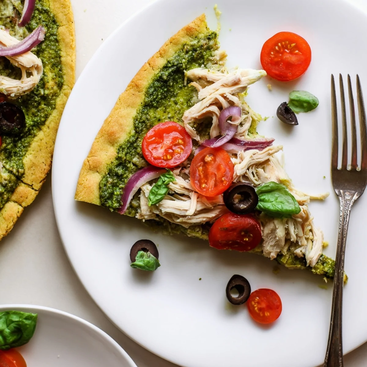 Slice of Chicken Pesto Paleo Pizza topped with juicy tomatoes, warm basil