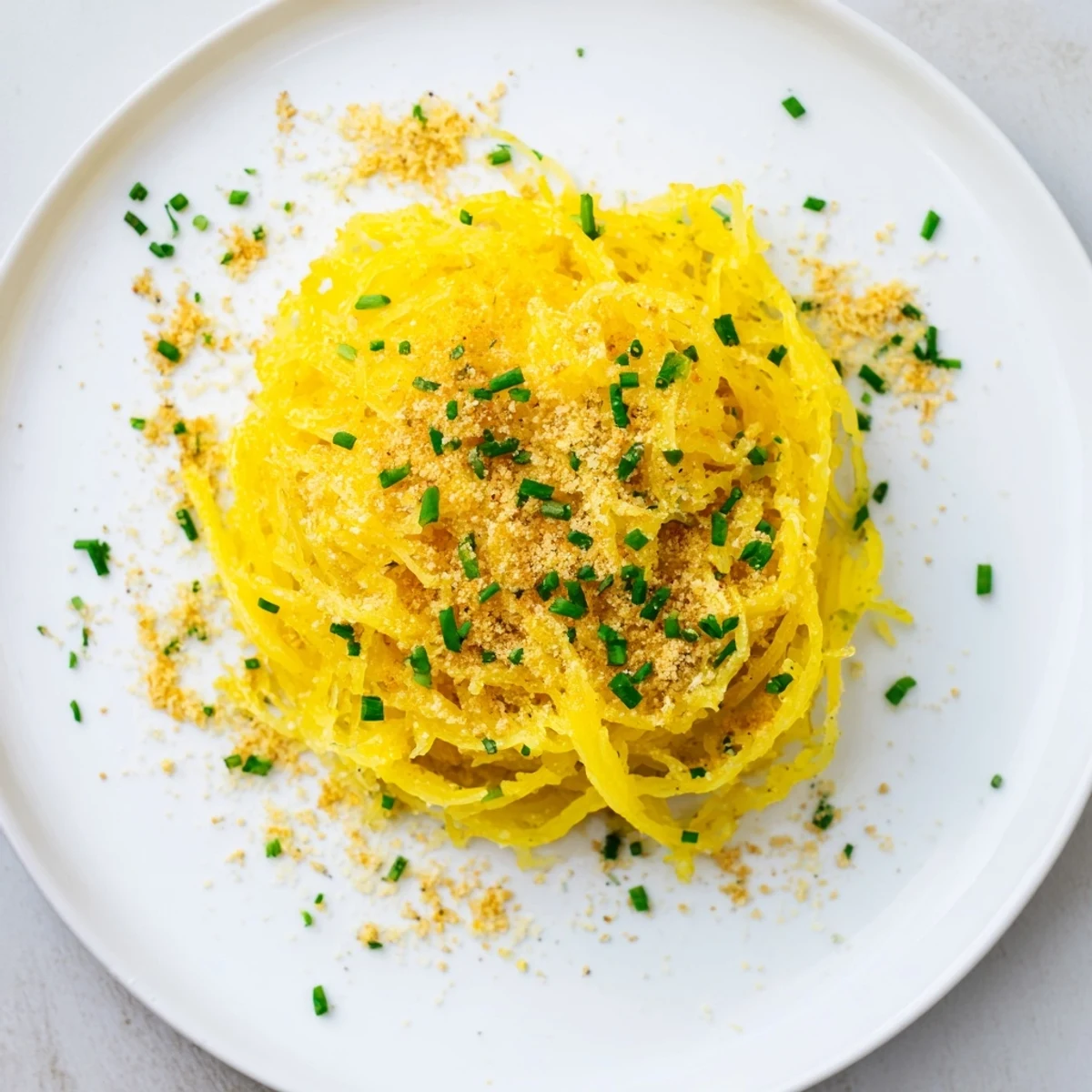 Creamy spaghetti squash mac cheese topped with golden breadcrumbs and fresh chives in a white baking dish