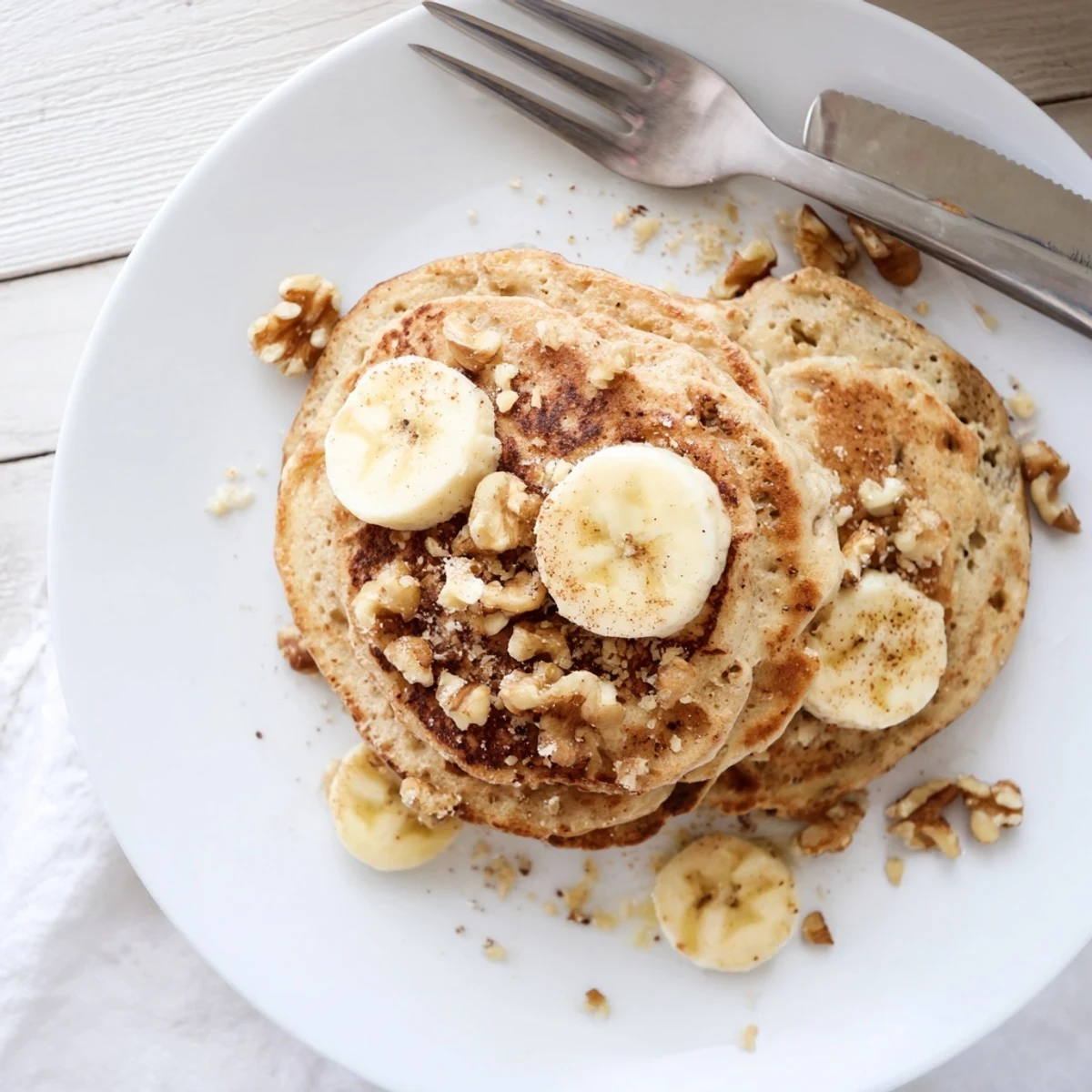 Golden stack of protein banana pancakes topped with fresh berries and maple syrup