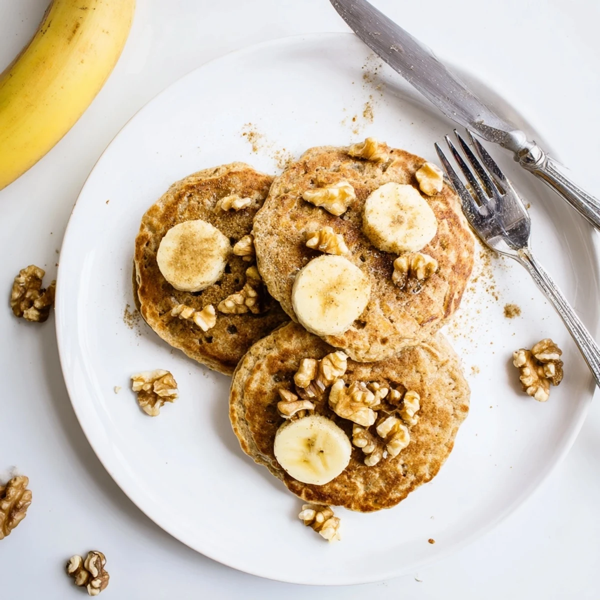 Healthy breakfast plate with protein banana pancakes dusted with cinnamon and walnuts