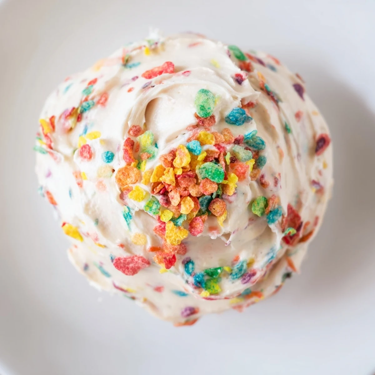Whipped butter frosting dotted with vibrant Fruity Pebbles cereal perfect for birthday cakes