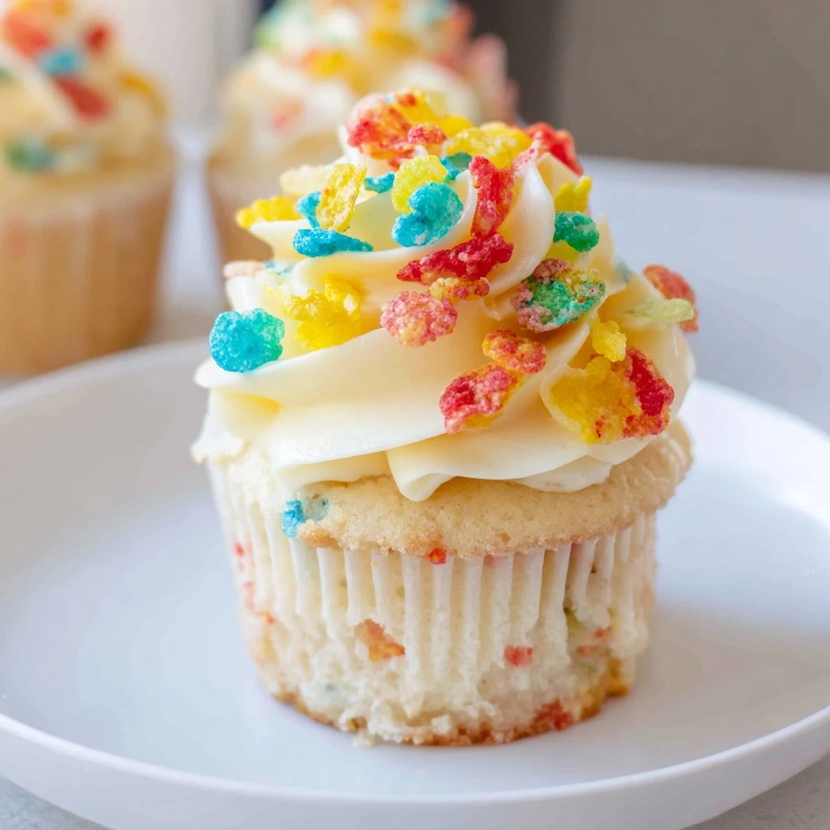 Colorful Fruity Pebbles Cereal Frosting piped on vanilla cupcakes, crunchy garnish.