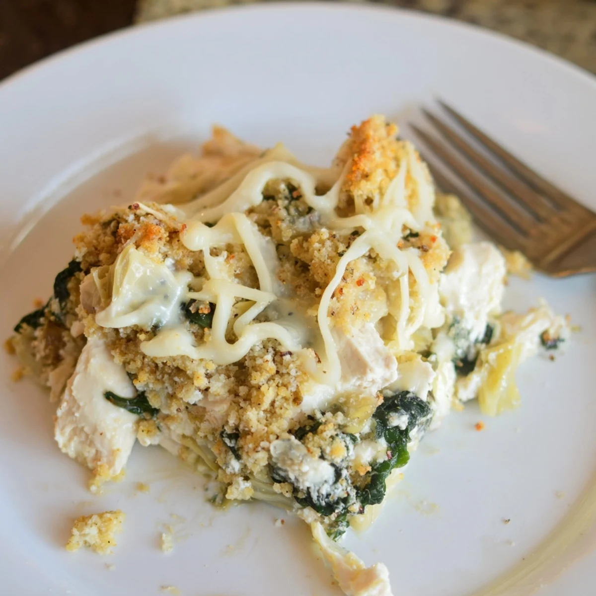 Hearty, creamy Spinach Artichoke Chicken Casserole, spinach and artichoke visible.