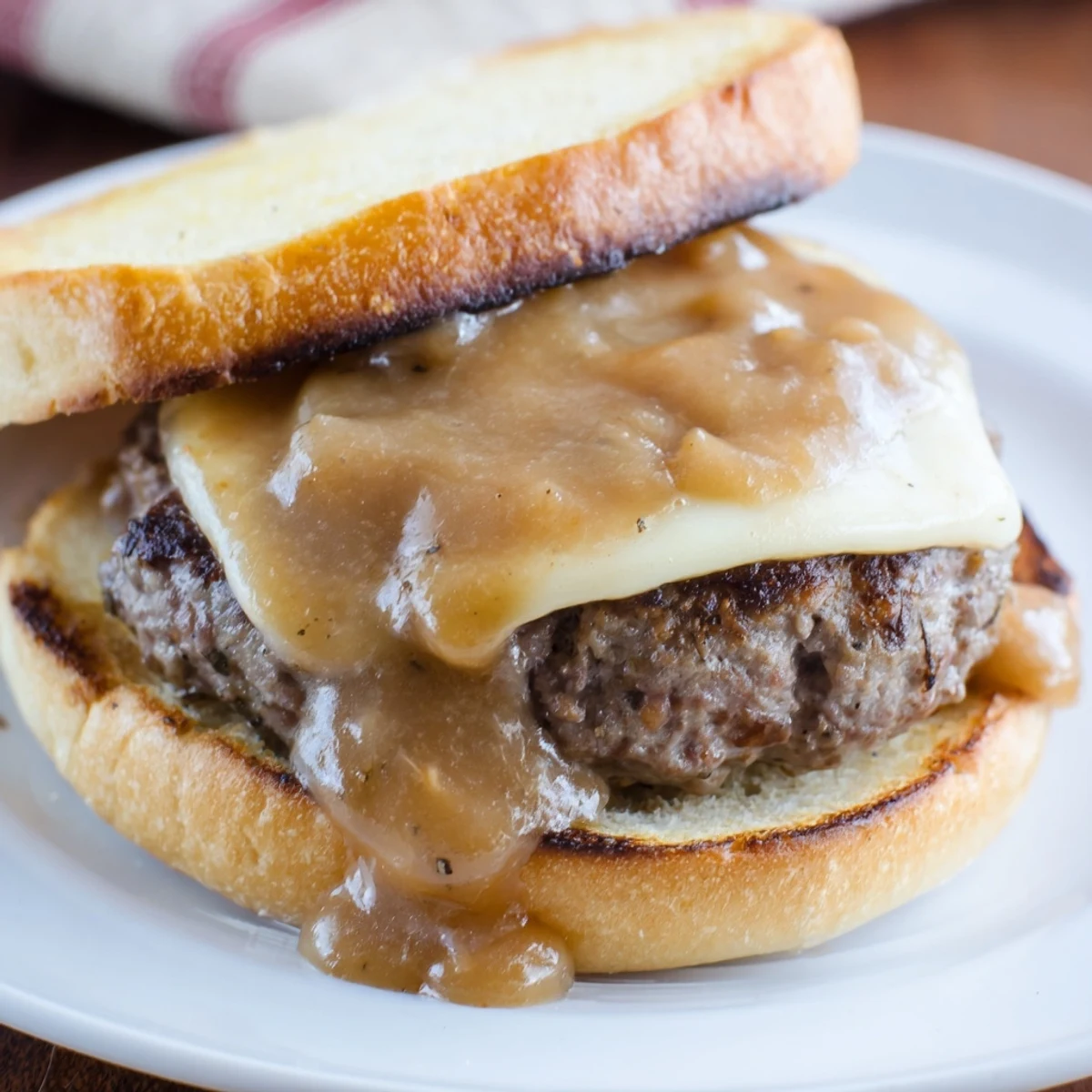 Juicy smothered hamburger steak sandwiches dripping with savory onion gravy on toasted rolls