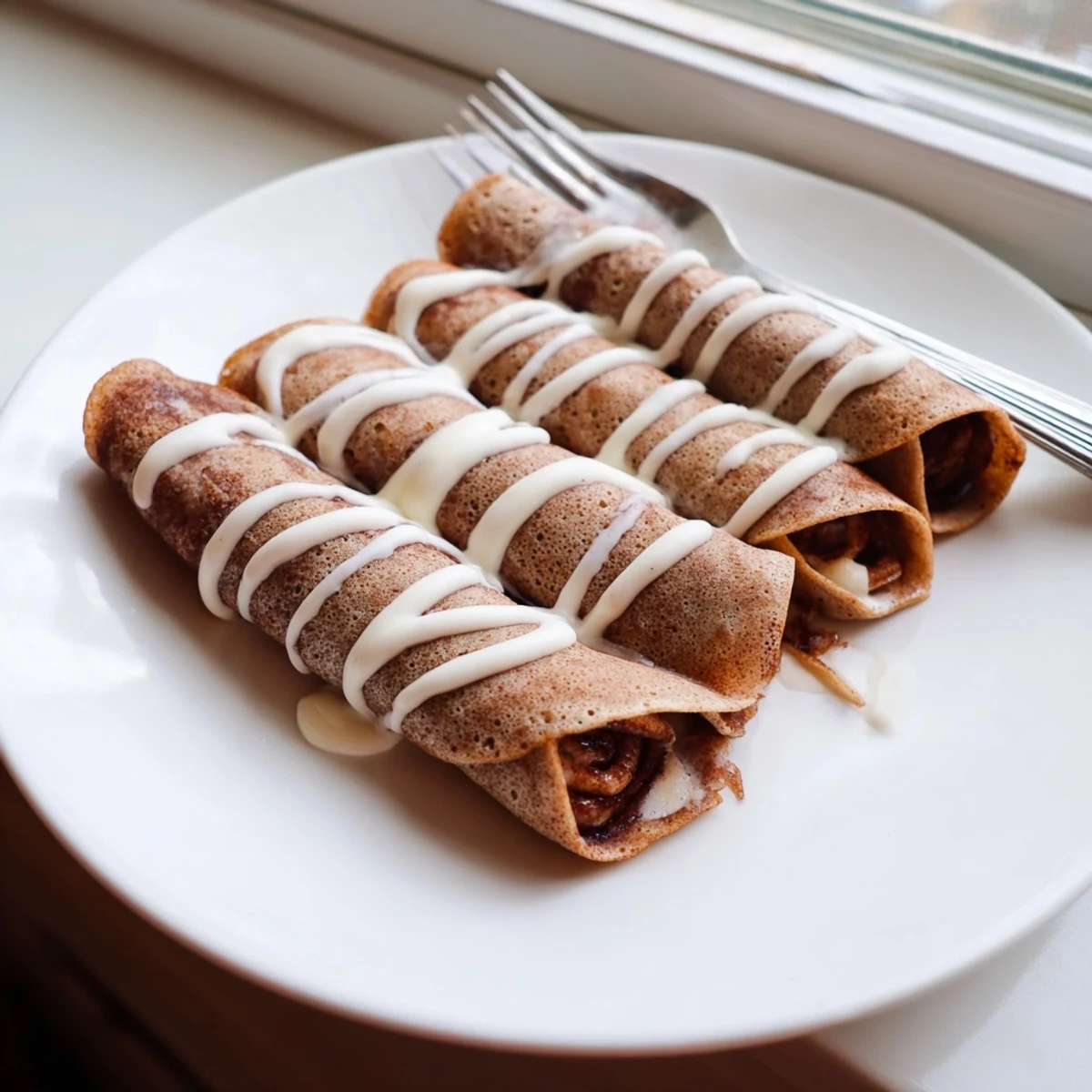 Close-up of cinnamon roll protein crepes oozing warm cream cheese swirl served with fresh berries