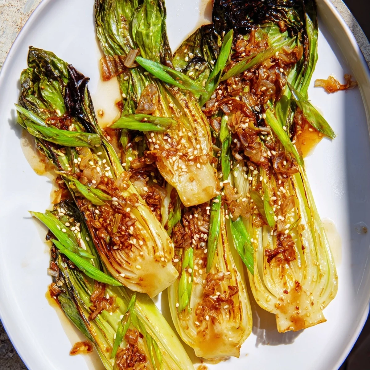 Crisp caramelized garlic bok choy in a cast iron skillet topped with sesame seeds