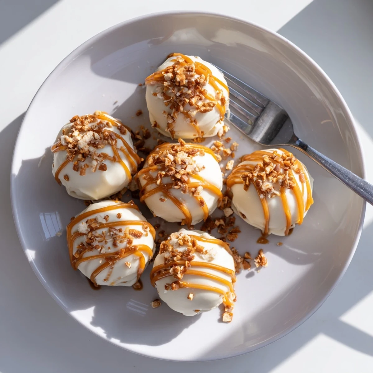 Creamy salted caramel pretzel cheesecake balls drizzled with golden caramel on a rustic tray