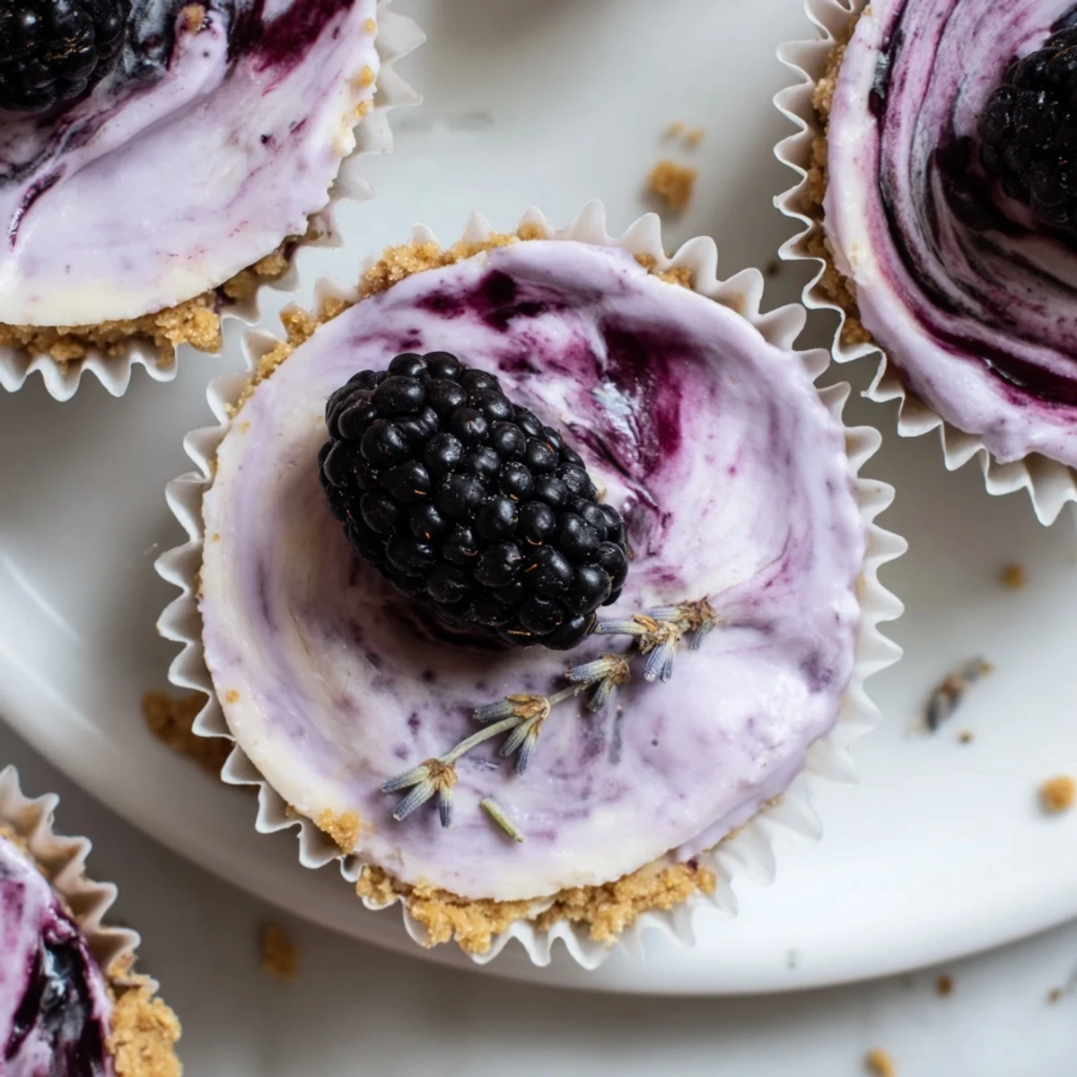 Silky mini blackberry lavender cheesecakes topped with glossy berry sauce in muffin liners