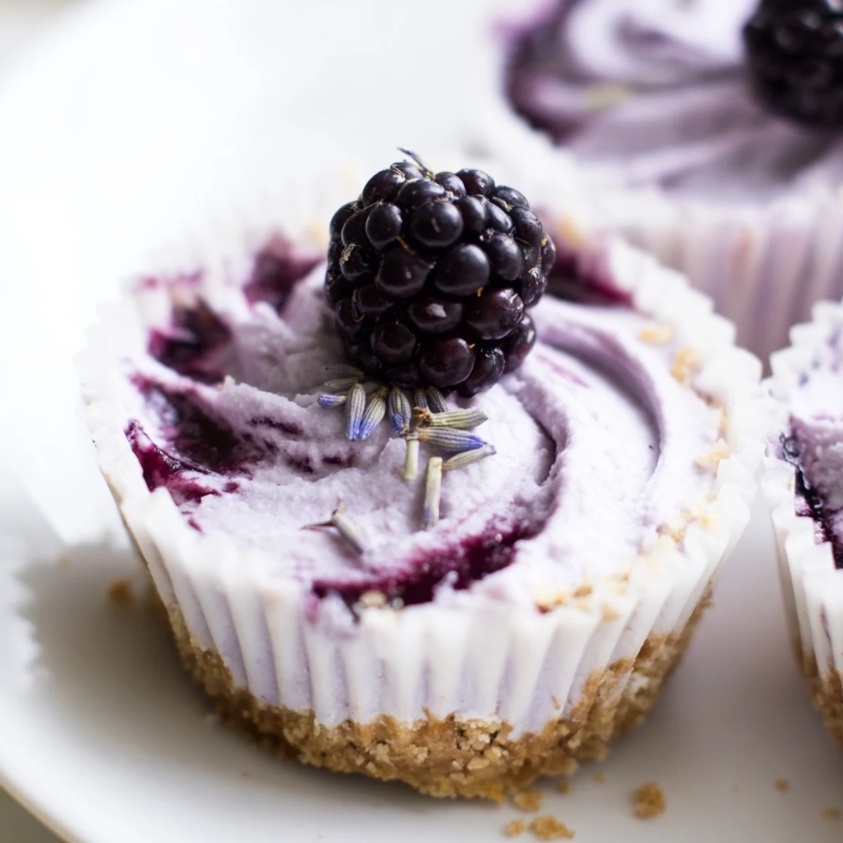 Individual blackberry lavender cheesecakes crowned with jewel-toned berry compote and fresh lavender sprigs