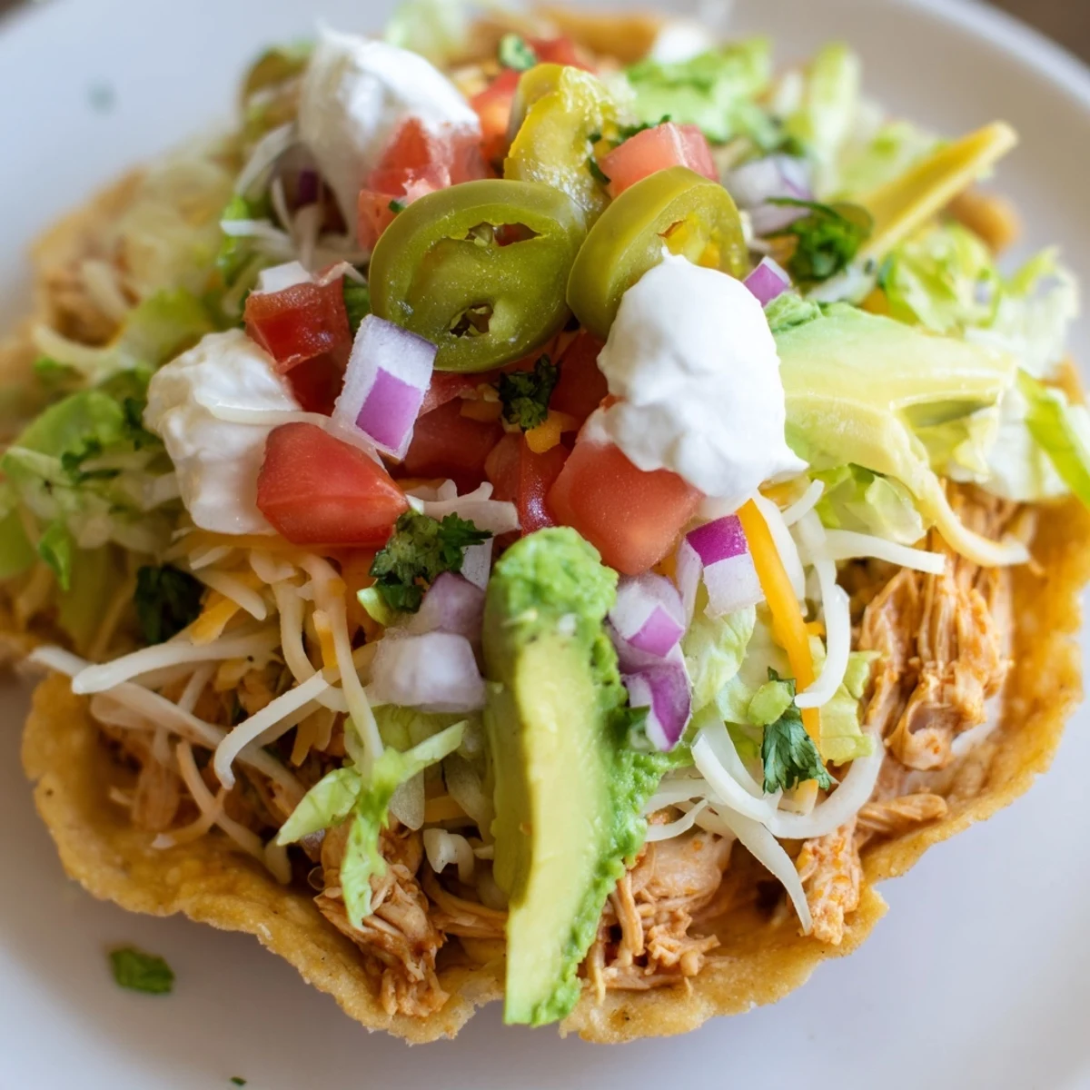 Golden chicken tostadas loaded with fresh toppings and creamy sour cream.