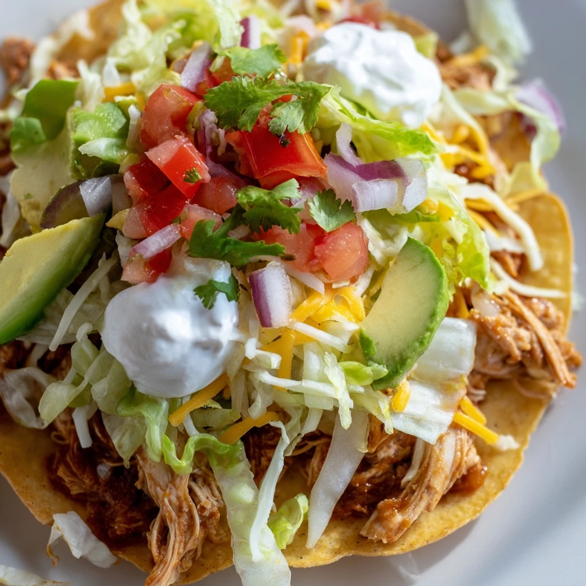 Crispy chicken tostadas topped with vibrant lettuce, cheese, and sliced avocado.