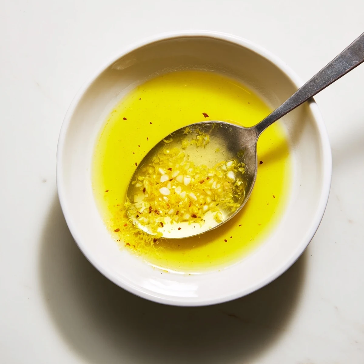 Close-up of Lemon Vinaigrette whisking with olive oil and fresh herbs