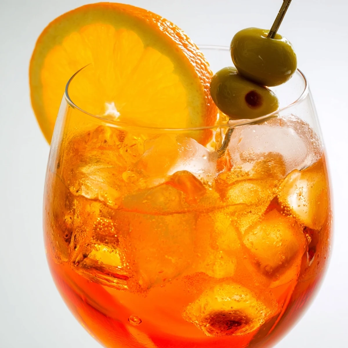 Vibrant orange Spritz cocktail garnished with fresh slice on ice.  