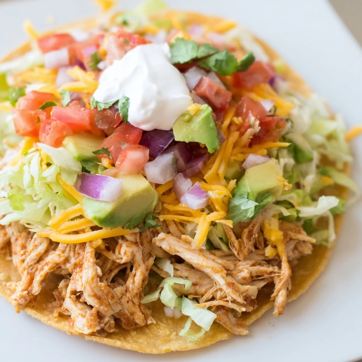 Juicy shredded chicken on crunchy tostadas served with avocado and lime wedges.