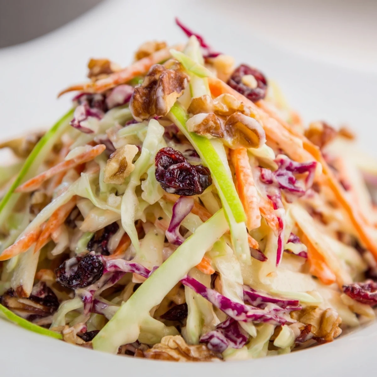 Colorful Cranberry Apple Coleslaw topped with crunchy walnuts in a white bowl  