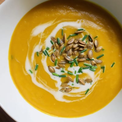 Steaming bowl of Winter Squash Soup with Apple, featuring velvety puree and a swirl of coconut milk.