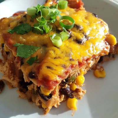 This hearty Mexican-inspired Chicken Enchilada Casserole features soft corn tortillas, black beans, and corn, served with fresh lime wedges.
