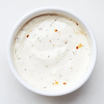 Dip into this hot honey ranch crispy chicken tenders sauce, garnished with dill and paprika.