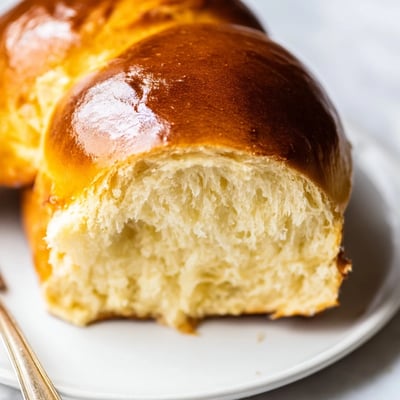 A loaf of Milk Brioche cooling on a rack with a tender, pillowy crumb visible.