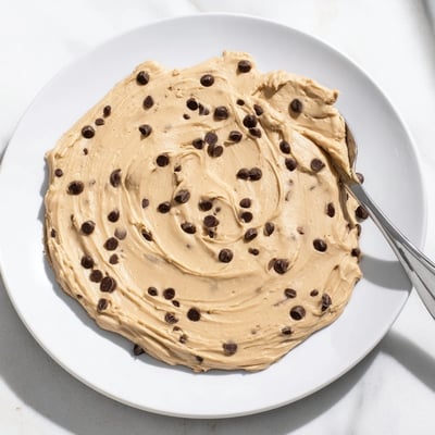 Thick, brown sugar frosting tasting like classic cookie dough, swirled on a chocolate cake slice.