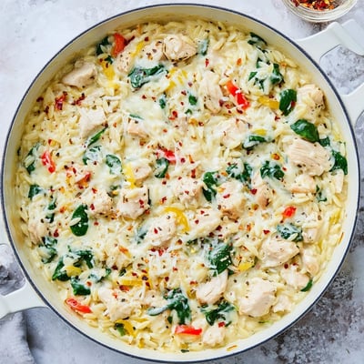 Tender chicken and orzo pasta bubbling in a rich cheese sauce with diced red bell pepper