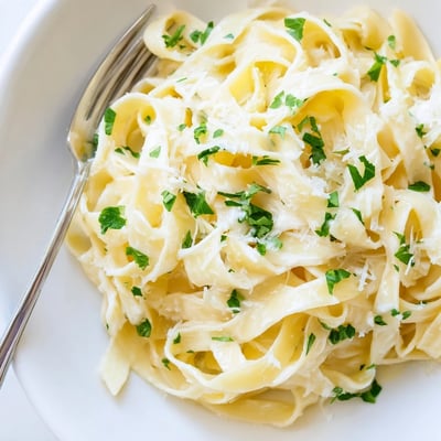 Creamy homemade fettuccine Alfredo plated with white sauce and extra grated Parmesan cheese on top