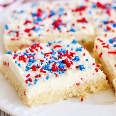 Patriotic sugar cookie bars with fluffy vanilla frosting and festive sprinkles, perfect for summer Fourth of July celebrations and parties