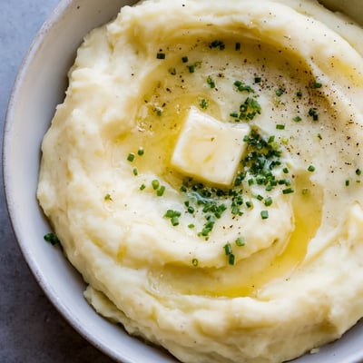 Smooth velvety mashed potatoes piled high and garnished with fresh snipped chives