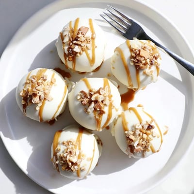 Golden-dipped salted caramel pretzel cheesecake balls coated in crunchy crushed pretzels with flaky salt