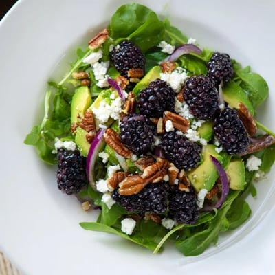 Vibrant blackberry avocado salad topped with toasted pecans and red onion slices  