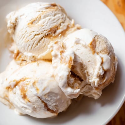 Scoop of halal salted caramel ice cream melting on a chilled dessert plate.  